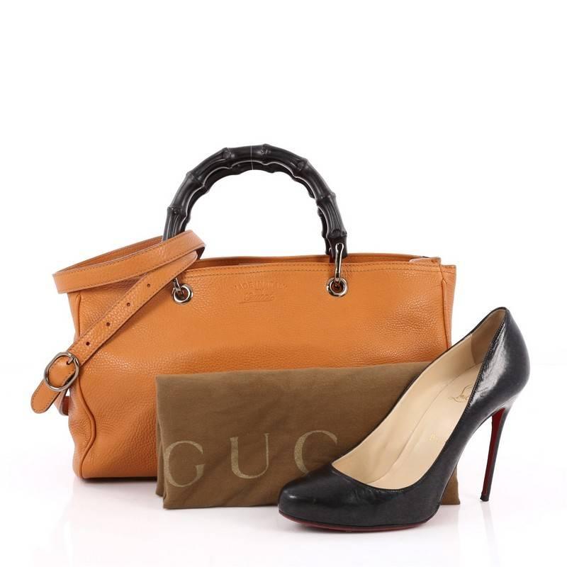 This authentic Gucci Bamboo Shopper Tote Leather Medium is a classic must-have. Crafted from orange leather, this simple yet stylish tote features Gucci's signature sturdy bamboo handles, protective base studs, stamped logo at the front, and gold