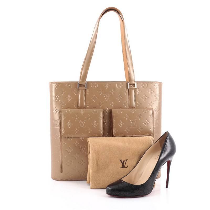 This authentic Louis Vuitton Mat Wilwood Handbag Monogram Vernis is an elegant tote for on-the-go use. Crafted in beige monogram vernis, this structure accessory features dual-flat vachetta leather handles, two exterior front flap pocket, and
