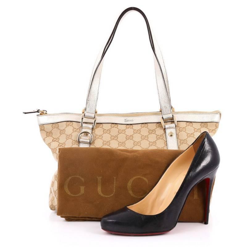 This authentic Gucci Abbey Tote GG Canvas Medium is ideal for everyday use. Constructed in beige GG canvas, this simple tote features dual flat leather handles, light gold leather trims, protective base studs and polished gold-tone hardware accents.