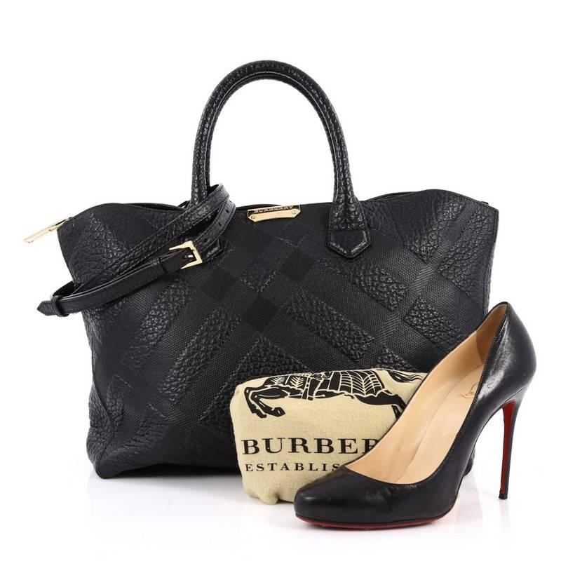 This authentic Burberry Dewsbury Convertible Tote Embossed Check Leather Medium is a timeless and refined satchel made for everyday use. Crafted from black leather with embossed check details, this chic bag features dual-rolled leather handles, a