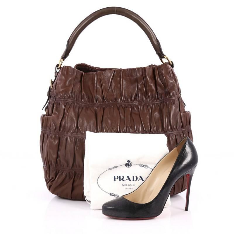 This authentic Prada Gaufre Side Pocket Hobo Nappa Leather Large is a stylish and easy-to-carry bag. Crafted from brown ruched nappa leather, this hobo features a rolled leather handle, two exterior side flat pockets, Prada logo on the side and