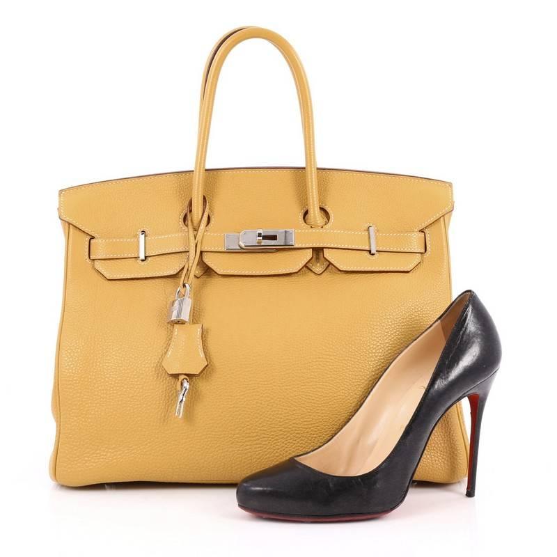 This authentic Hermes Birkin Handbag Curry Togo with Palladium Hardware 35 showcases subtle elegance. Finely crafted in beautiful, curry yellow togo leather, this piece features dual-rolled top handles, frontal flap, turn-lock closure, protective