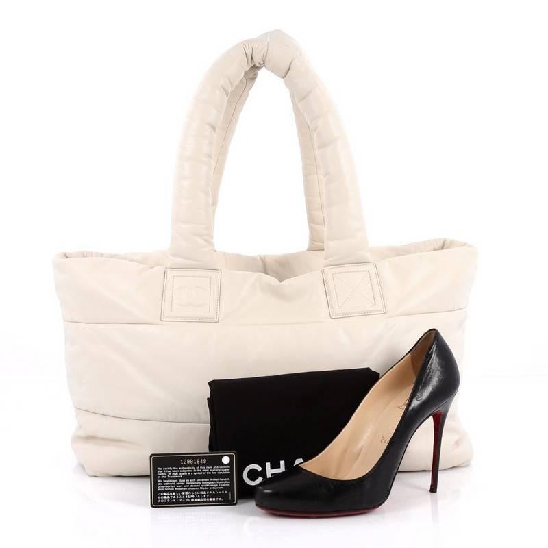 This authentic Chanel Coco Cocoon Reversible Tote Quilted Lambskin Medium is a highly sought after piece from Lagerfeld's fun and chic Coco Cocoon line. Crafted from off-white leather, this sporty-chic tote features padded top handles, interlocking