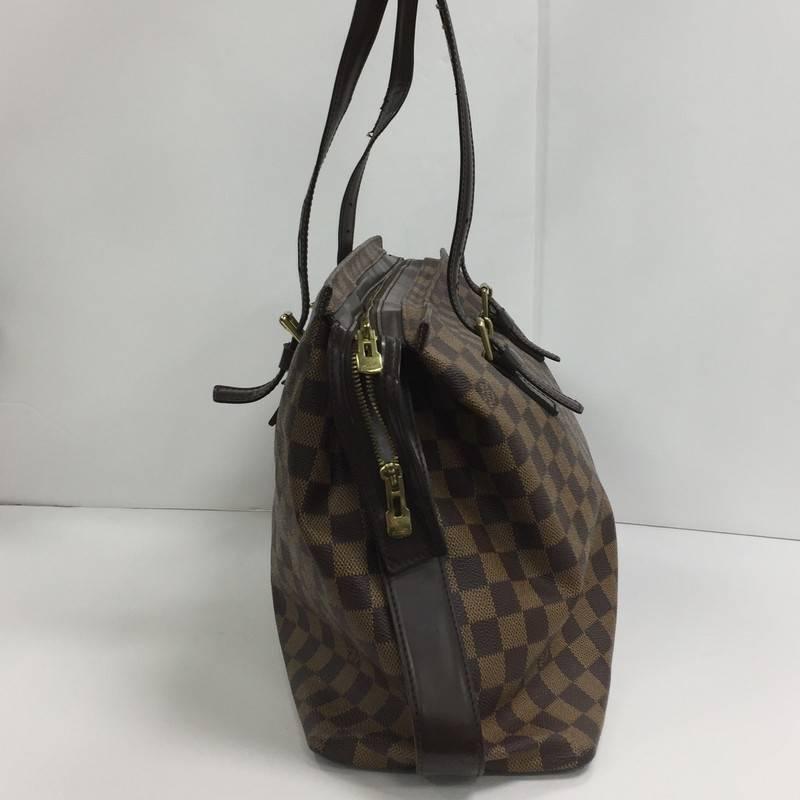 This authentic Louis Vuitton Chelsea Handbag Damier combines Louis Vuitton's classic style with sophisticated functionality. Constructed from the popular damier ebene coated canvas with dark brown leather trims, this tote features a simple