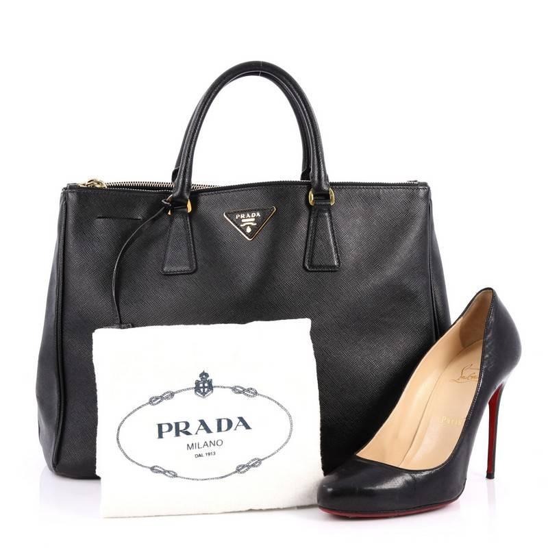 This authentic Prada Double Zip Lux Tote Saffiano Leather Large is the perfect bag to complete any outfit. Crafted from black saffiano leather, this boxy tote features side snap buttons, raised Prada logo, dual-rolled leather handles and gold-tone