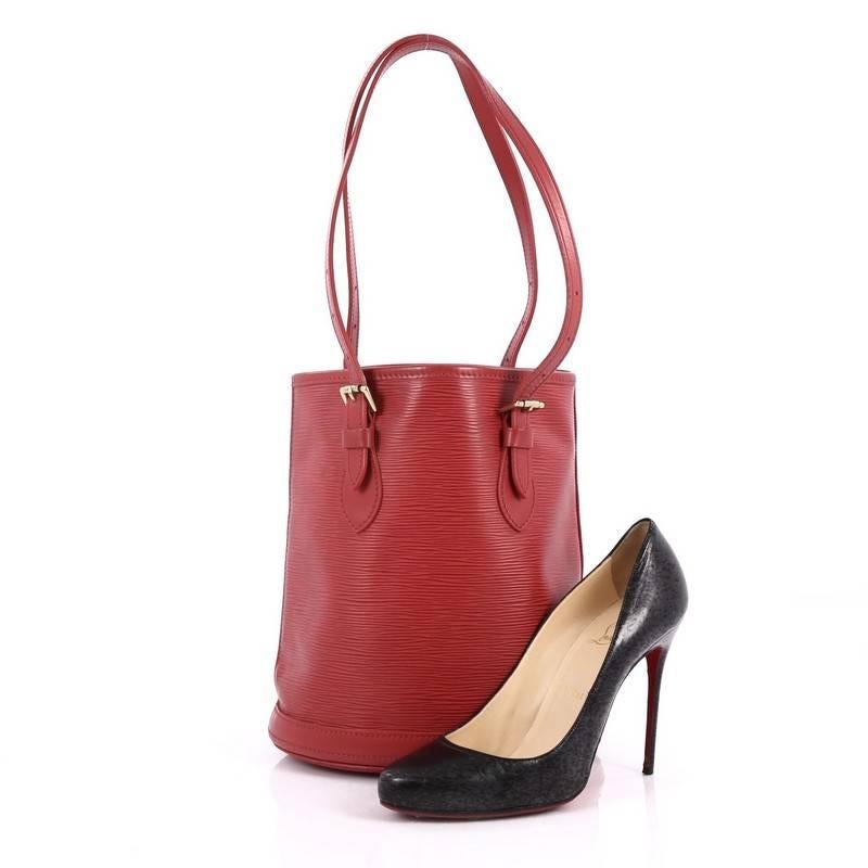 This authentic Louis Vuitton Petit Bucket Bag Epi Leather is a classic and timeless accessory made for everyday use. Crafted from red epi leather, this structured bag features reinforced oval base that keeps the bag free-standing, adjustable belt