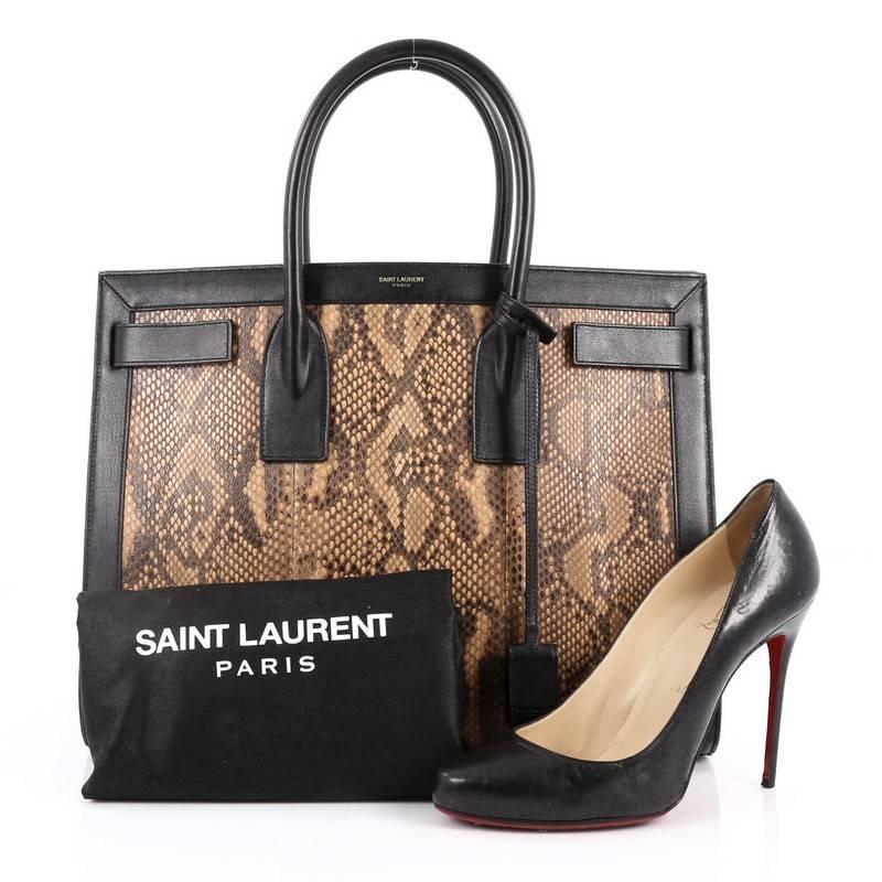 This authentic Saint Laurent Sac De Jour Handbag Python Medium is an interpretation of a French day bag with a minimalist design perfect for everyday use. Crafted from genuine brown and beige python skin with black leather trims, this bag features