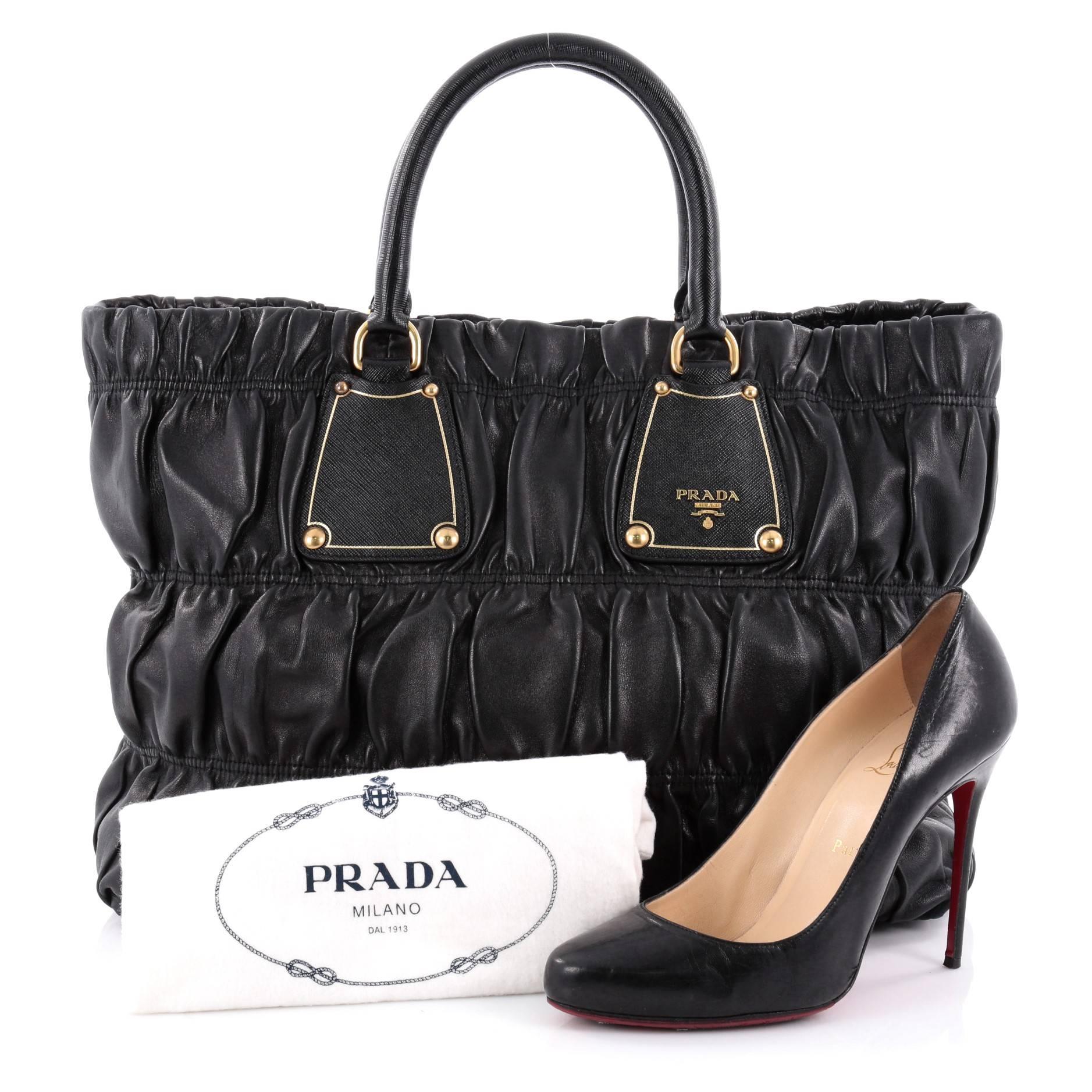 This authentic Prada Gaufre Tote Nappa Leather Large is a versatile contemporary chic day bag to have by your side perfect for your daily excursions. Crafted from pleated black nappa leather, this stylish bag features dual-rolled leather handles,
