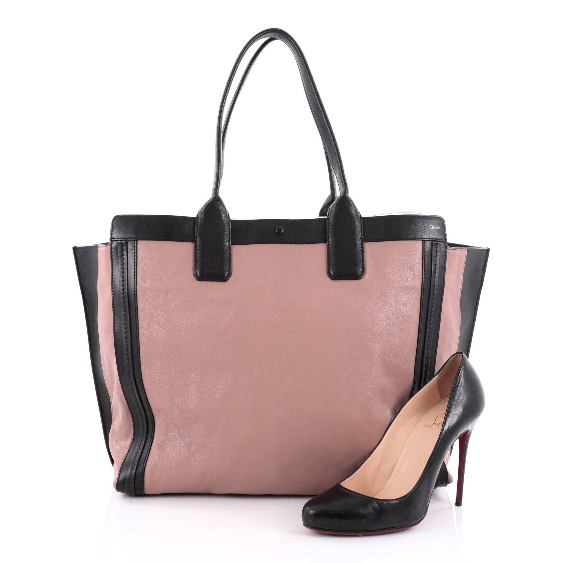 This authentic Chloe Alison East West Tote Leather Medium is a perfect everyday bag. Crafted from mauve leather with black leather trims, this tote features a winged silhouette, dual tall flat handles, subtle stamped Chloe name, and gold-tone