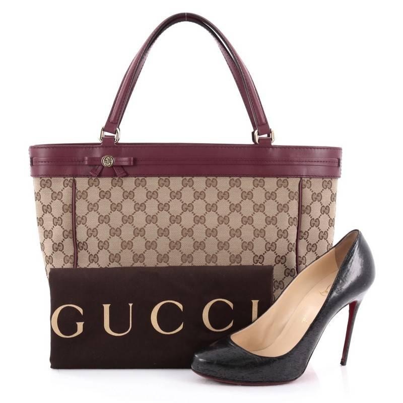 This authentic Gucci Mayfair Tote GG Canvas Wide is a chic and classic accessory made for everyday use. Crafted from beige GG monogram fabric with leather trims, this bag features dual flat leather handles, interlocking GG emblem and bow, protective