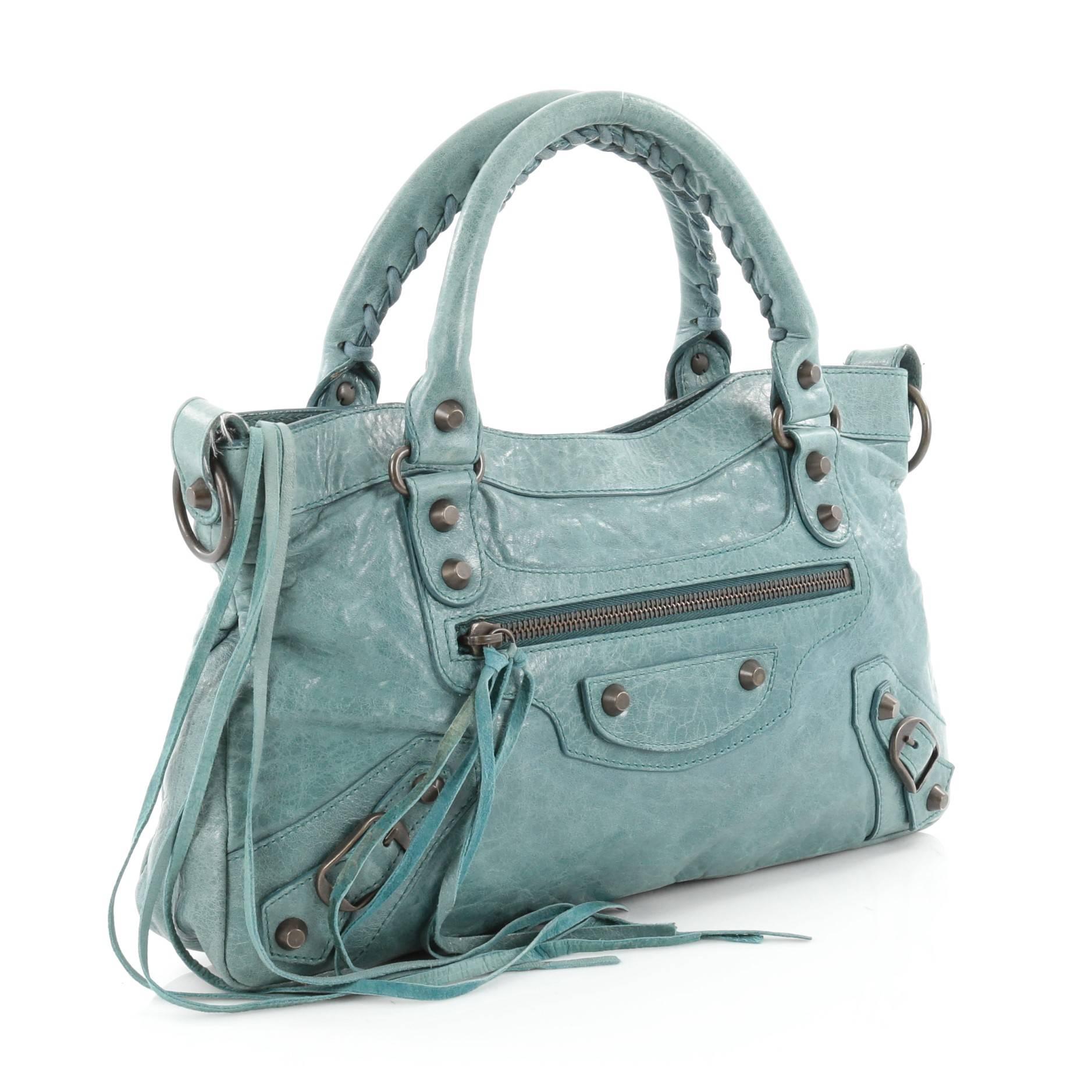 This authentic Balenciaga First Covered Classic Studs Handbag Leather is an easy-to-carry accessory that can be paired with any outfit. Constructed from light turquoise leather, this everyday bag features braided woven handles, long fringe