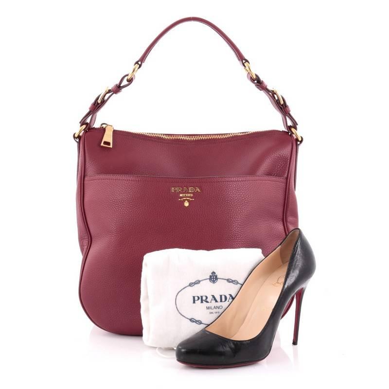 This authentic Prada Zip Pocket Hobo Vitello Daino Large is a classic design perfect for everyday use. Crafted in cranberry red vitello daino leather, this hobo features single loop leather handle, gold Prada logo at the center, exterior front