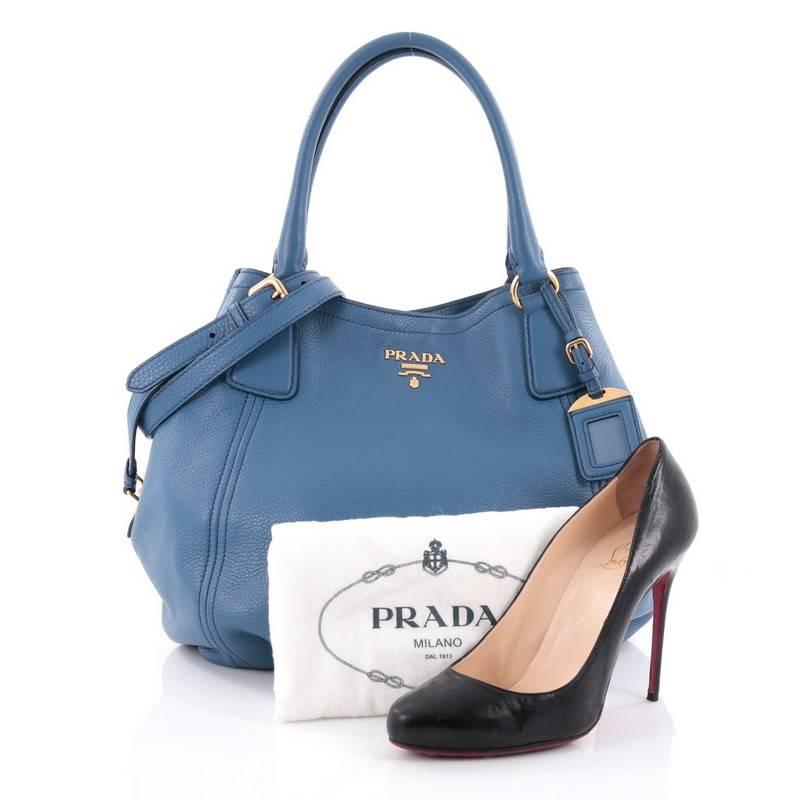 This authentic Prada Convertible Satchel Vitello Daino Medium is elegant in its simplicity and structure. Crafted from blue vitello daino leather, this tote features dual-rolled leather handles, raised Prada logo, side button snaps, protective base