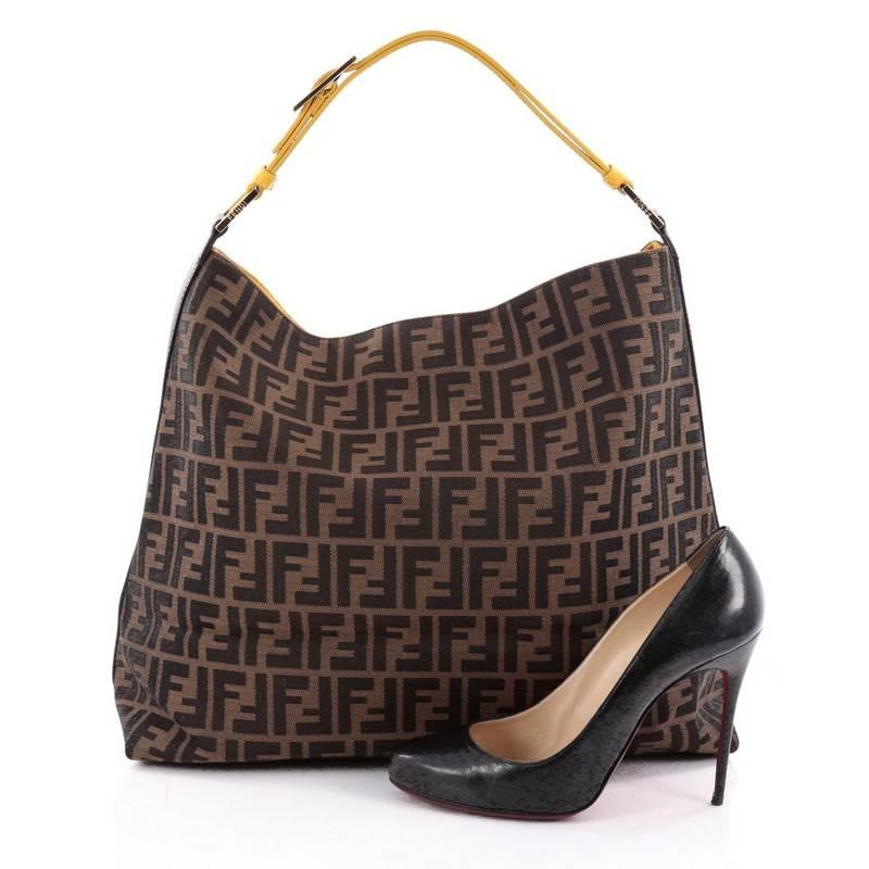 This authentic Fendi Buckle Strap Hobo Zucca Canvas Large is a chic hobo bag ideal for your everyday looks. Crafted from Fendi zucca-print canvas, this luxe hobo features an adjustable logo-embossed buckled shoulder strap, yellow leather trims and