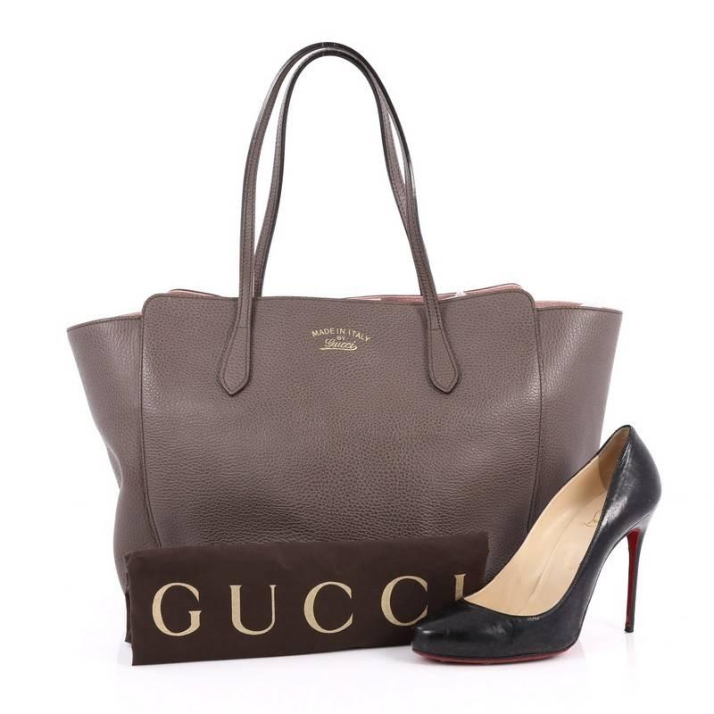 This authentic Gucci Swing Tote Leather Medium is modern and sophisticated in design. Crafted in dark grey leather, this elegant tote features tall dual-slim handles, Gucci stamped logo at the front, expanded wing silhouette, and gold-tone hardware
