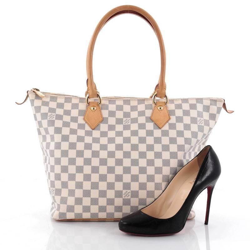 This authentic Louis Vuitton Saleya Handbag Damier MM is a mix of classic style with modern functionality. Crafted from damier azur canvas, this tote features dual rolled vachetta leather tall handles, structured base, and gold-tone hardware