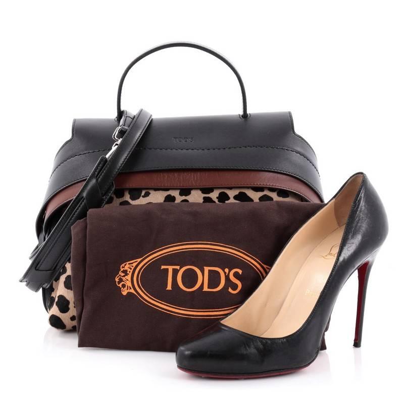 This authentic Tod's Convertible Wave Bag Printed Pony Hair with Leather Mini is a sartorial-inspired bag perfect for the modern fashionista. Crafted from printed pony hair and black and brown leather, this exotic bag features a flat leather top