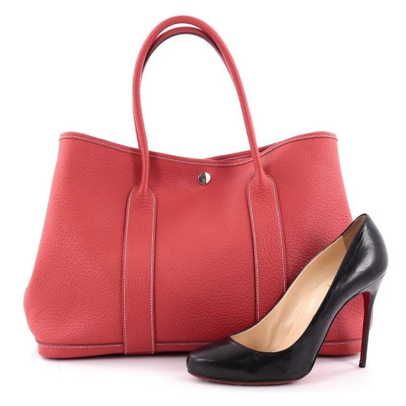 This authentic Hermes Garden Party Tote Leather 36 is an elegant and simple tote made for all seasons. Crafted from casaque red leather, this chic everyday tote features dual-rolled leather top handles, stand-out contrast stitching, palladium button
