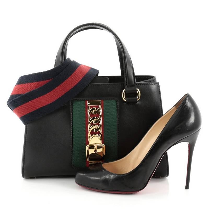 This authentic Gucci Sylvie Convertible Satchel Leather Medium is perfect for the modern fashionista. Crafted from black leather, this bag features dual flat leather handles, detachable leather shoulder strap, nylon Web detail with curb chain,