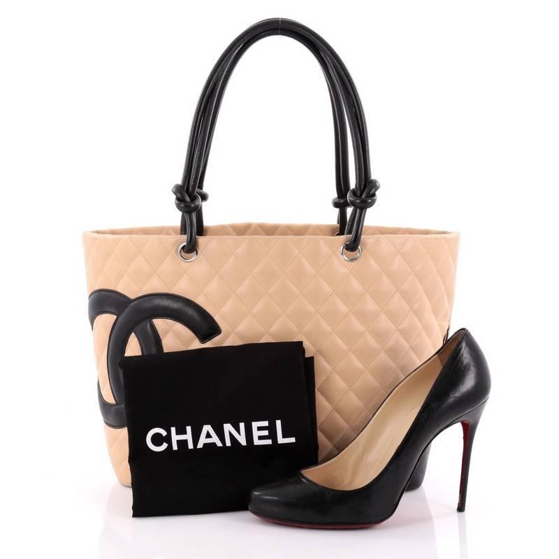 This authentic Chanel Cambon Tote Quilted Leather Large is finely crafted bag from the brand's Cambon Collection. Crafted from beige diamond quilted leather, this tote displays a black leather interlocking CC side logo, dual-rolled leather handles
