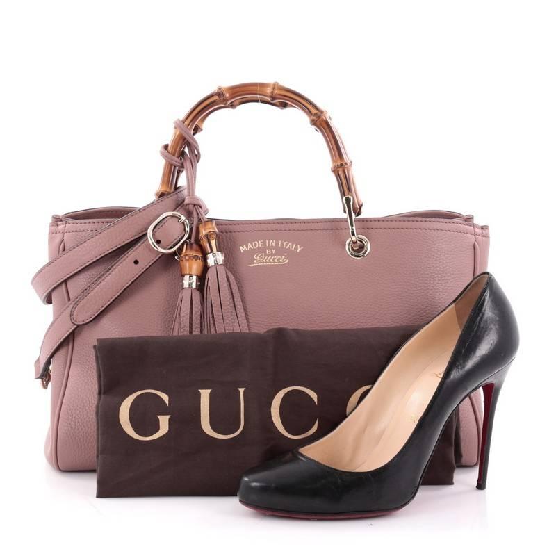 This authentic Gucci Bamboo Shopper Tote Leather Medium is a classic must-have. Crafted from mauve pink leather, this simple yet stylish tote features Gucci's signature sturdy bamboo handles, protective base studs, stamped logo at the front, and