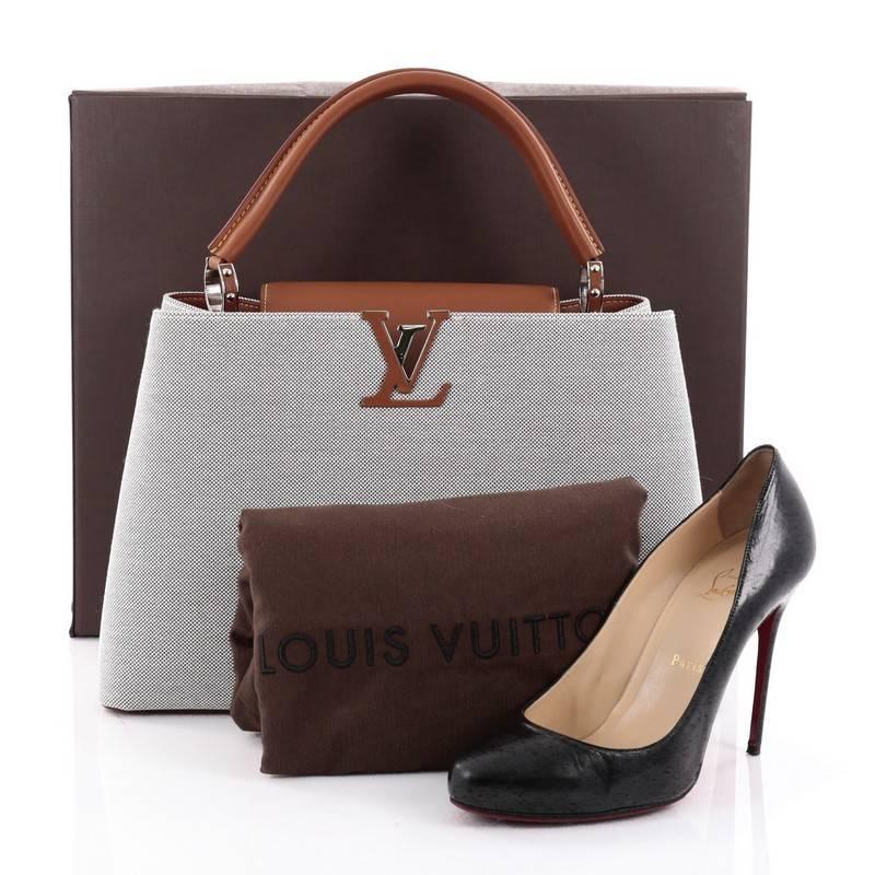 This authentic Louis Vuitton Capucines Handbag Canvas with Mateo Leather MM is sophisticated and ladylike luxurious bag inspired by the brands' Parisian heritage. Crafted from gray capucines Canvas with Mateo leather, this chic, stand-out bag