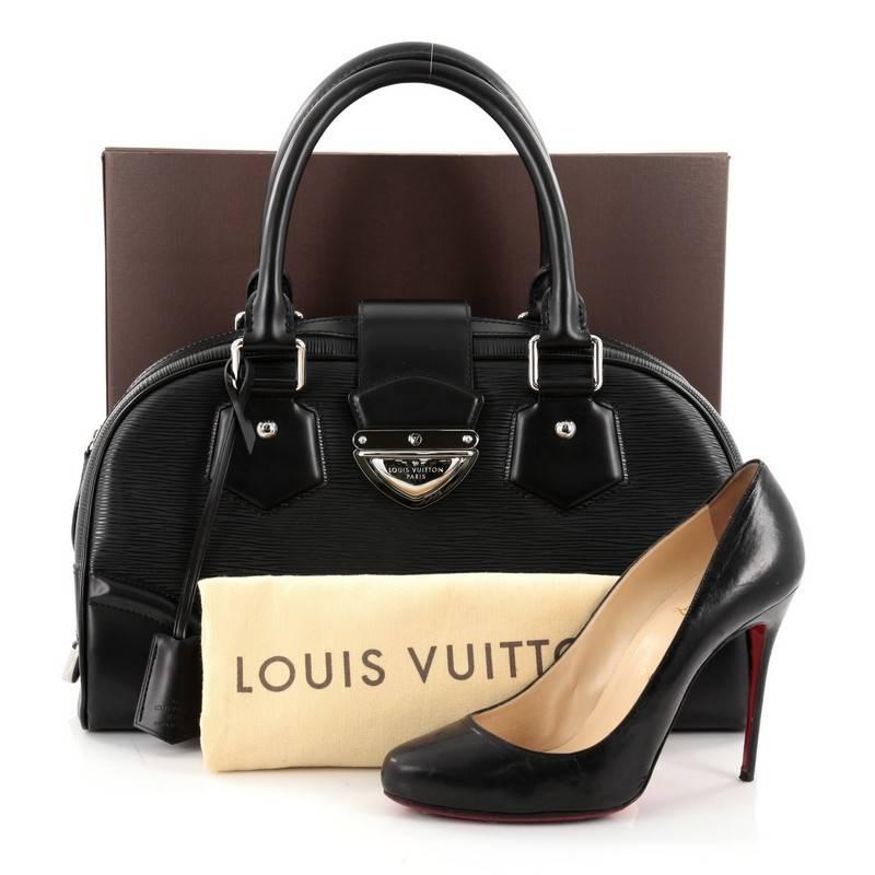 This authentic Louis Vuitton Montaigne Bowling Bag Epi Leather GM is perfect for everyday use. Crafted from black epi leather, this structured bowler features dual-rolled leather handles, protective base studs and silver-tone hardware accents. Its