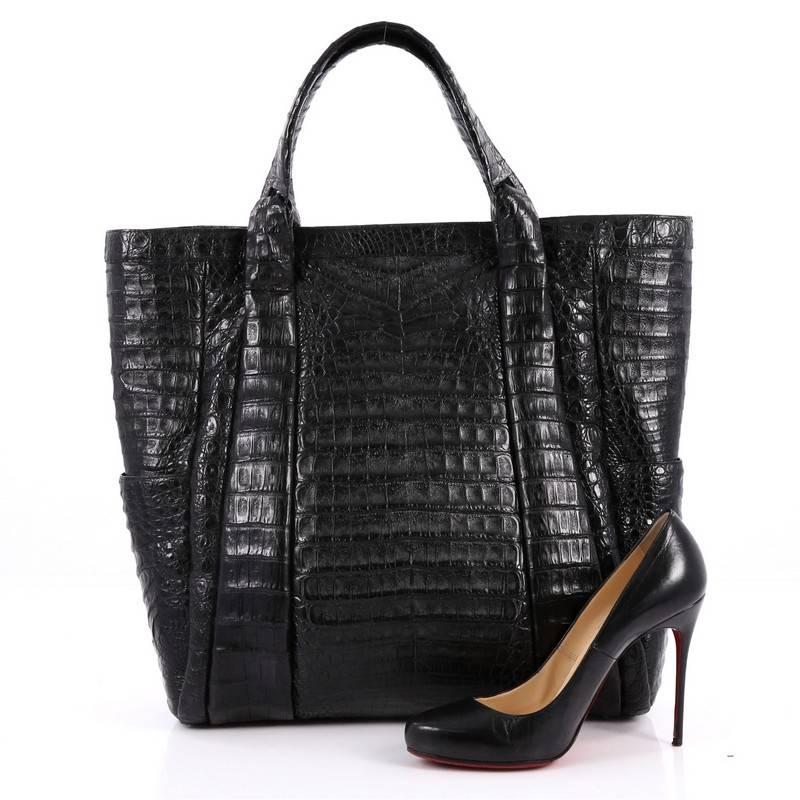This authentic Nancy Gonzalez Tote Crocodile Large is the perfect combination of luxurious style and a polished aesthetic made for the modern woman. Crafted from genuine black crocodile skin with pleated detailing, this structured tote features