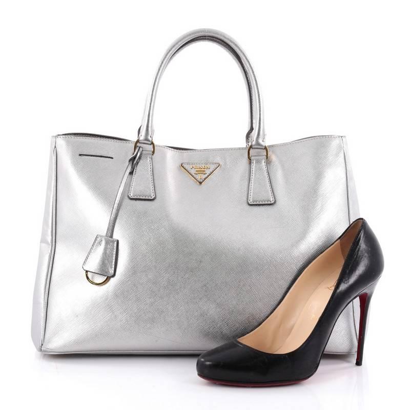 This authentic Prada Lux Open Tote Saffiano Leather Large is elegant in its simplicity and structure. Crafted from silver saffiano leather, this sturdy and spacious tote features dual-rolled handles, gusseted side with snap buttons, iconic inverted