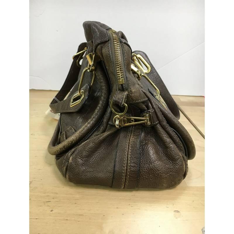 This authentic Chloe Paraty Top Handle Bag Leather Small mixes everyday style and functionality perfect for the modern woman. Crafted from dark brown leather, this versatile bag features dual flat handles, piped trim details, side twist locks, and