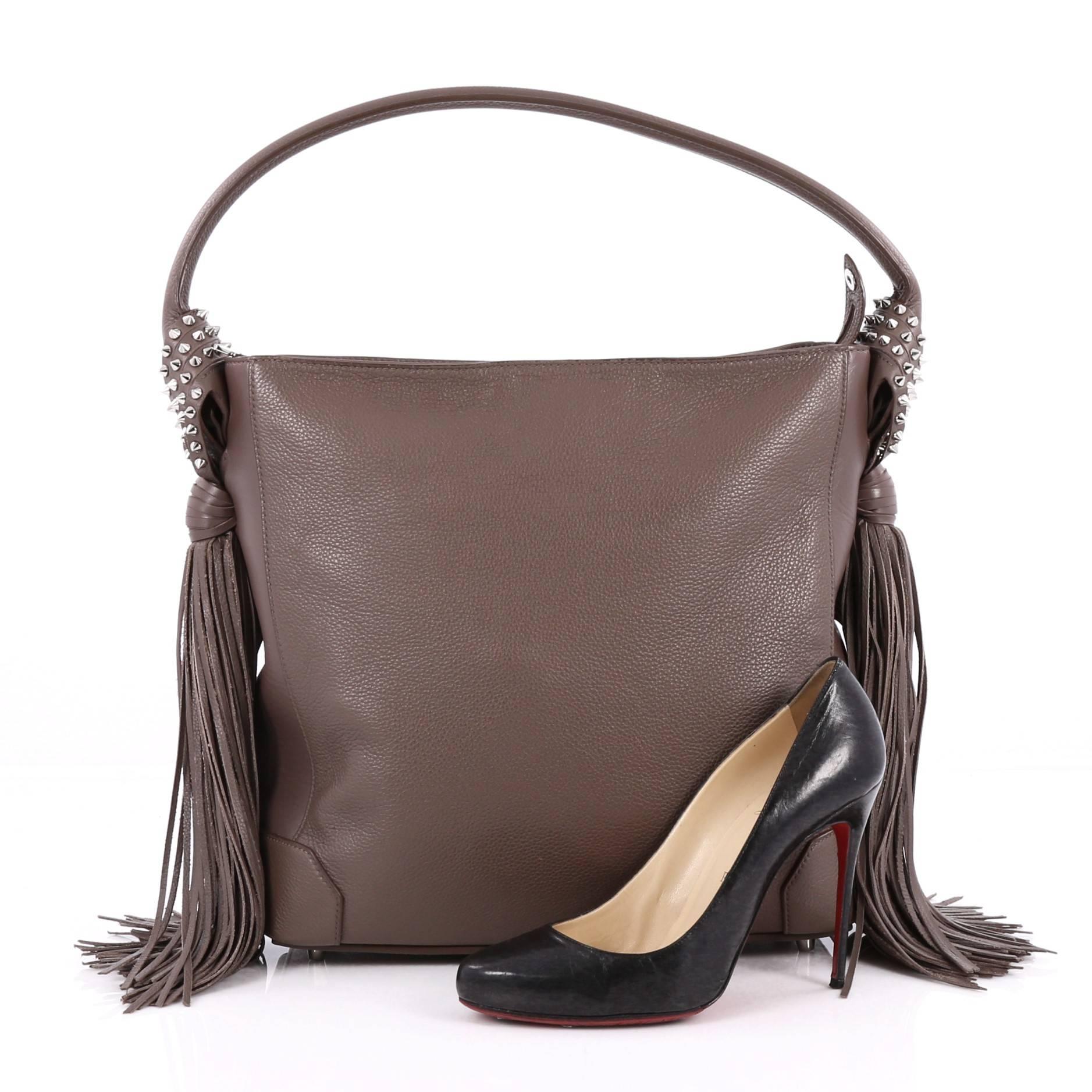 This authentic Christian Louboutin Eloise Fringe Hobo Leather Medium is a supple slouchy bag that takes on a bohemian styling. Crafted from brown leather, this gorgeous bag features flat leather shoulder strap, swinging fringe and spiked sides, two