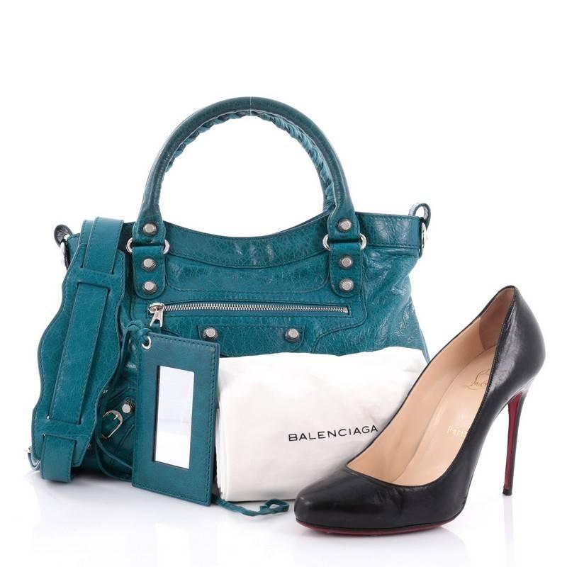 This authentic Balenciaga Town Giant Studs Handbag Leather is for the on-the-go fashionista. Constructed in teal leather, this popular bag features braided woven handles, long fringe details, front zipped pocket, buckle details, iconic Balenciaga