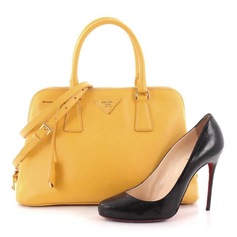 This authentic Prada Promenade Handbag Saffiano Leather Medium is elegant in its simplicity and structure. Crafted in yellow saffiano leather, this sleek dome-shaped satchel features dual-rolled handles, protective base studs, Prada logo at the