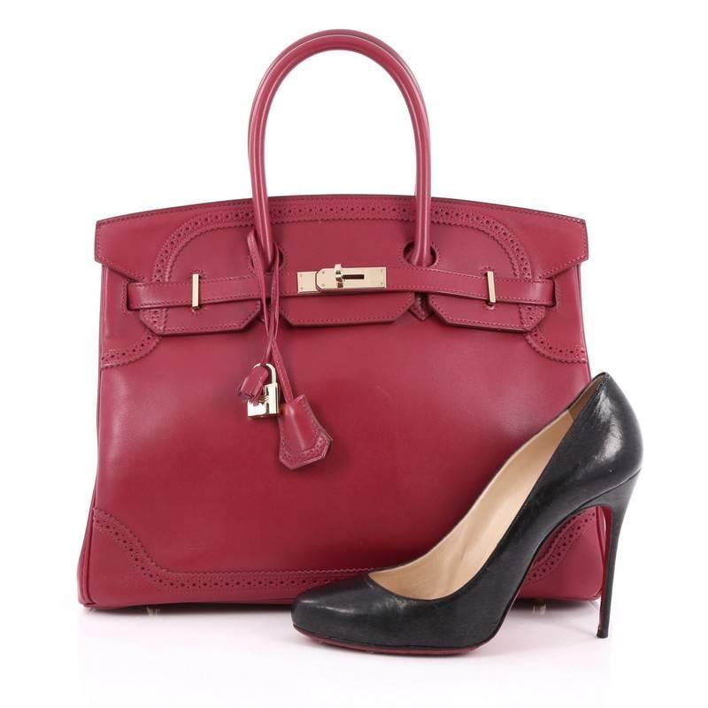 This authentic Hermes Birkin Ghillies Handbag Rubis Tadelakt with Gold Hardware 35 is a special edition piece that graces only a few closets. Crafted from rubis red leather, this coveted Birkin features dual-rolled handles, frontal flap, polished