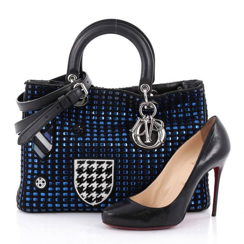 This authentic Christian Dior Diorissimo Tote Patch Embellished Metallic Tweed Large mixes a timeless and elegant design with kitschy, work-of-art design made for the modern woman. Crafted from blue and black woven tweed and leather with