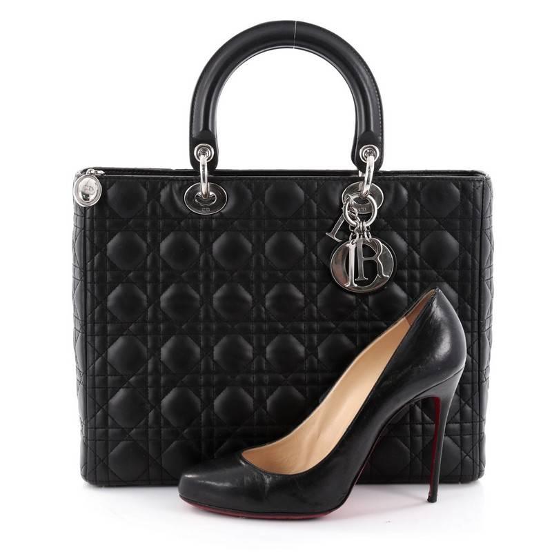 This authentic Christian Dior Lady Dior Handbag Cannage Quilt Lambskin Large is a classic staple that every fashionista needs in her wardrobe. Crafted from black lambskin leather in Dior's iconic cannage quilting, this boxy bag features dual-rolled