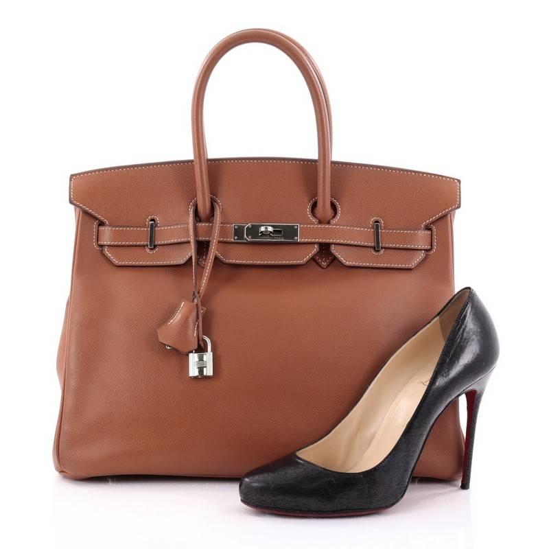 This authentic Hermes Birkin Handbag Gold Brown Epsom with Palladium Hardware 35 stands as one of the most-coveted bags. Constructed from scratch-resistant, iconic brown epsom leather, this stand-out tote features dual-rolled top handles, frontal