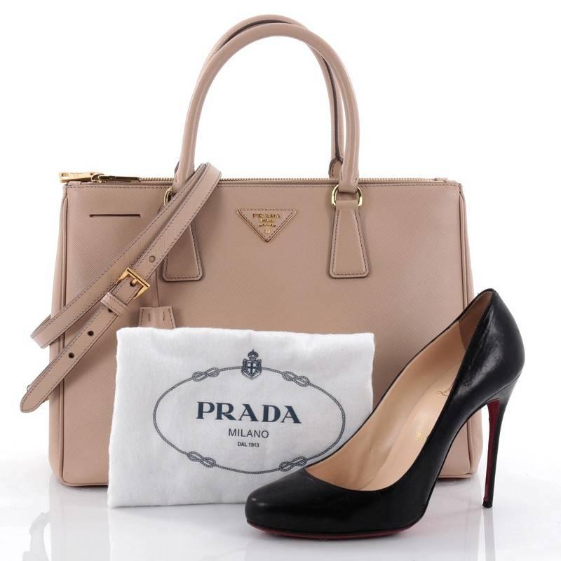 This authentic Prada Double Zip Lux Tote Saffiano Leather Medium is the perfect bag to complete any outfit. Crafted from beige saffiano leather, this boxy tote features side snap buttons, raised Prada logo, dual-rolled leather handles and gold-tone