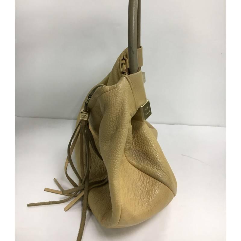 This authentic Chanel Vintage Dice Top Handle Bag Leather Medium is your perfect accessory to carry for your day or nights out. Crafted from beige leather this stylish bag features looping rolled shoulder strap with gold-tone dice ends, leather