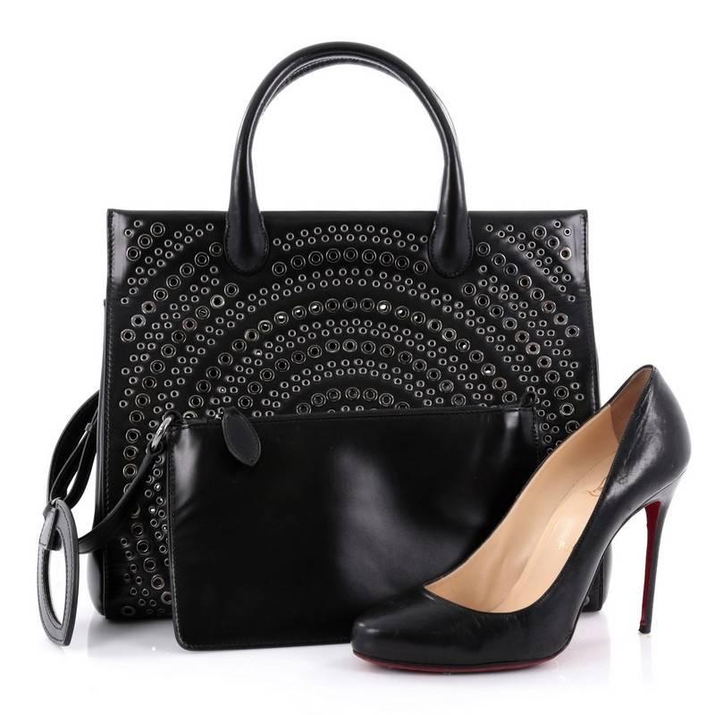 This authentic Alaia Snap Tote Grommet Embellished Leather Medium personifies the brand's quintessential sleek yet chic everyday style. Designed in black leather, this oversized tote features, dual-rolled handles, beautiful geometric laser cut with