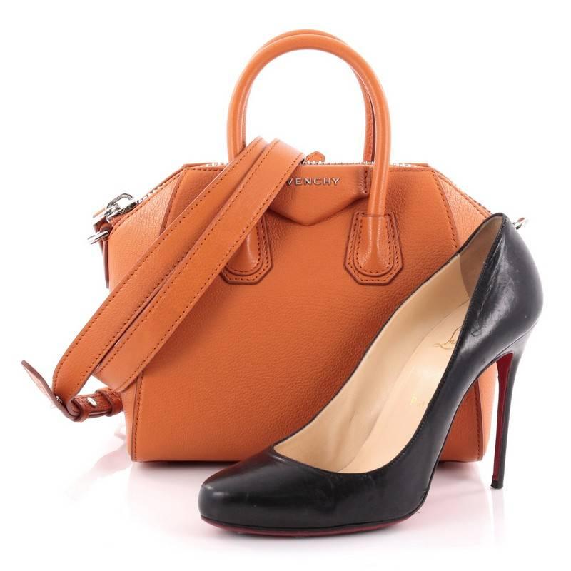 This authentic Givenchy Antigona Bag Leather Mini presents the brand's most iconic bag in a miniature version. Crafted from supple orange leather, this structured handle bag features the brand's signature envelope flap detail with silver Givenchy