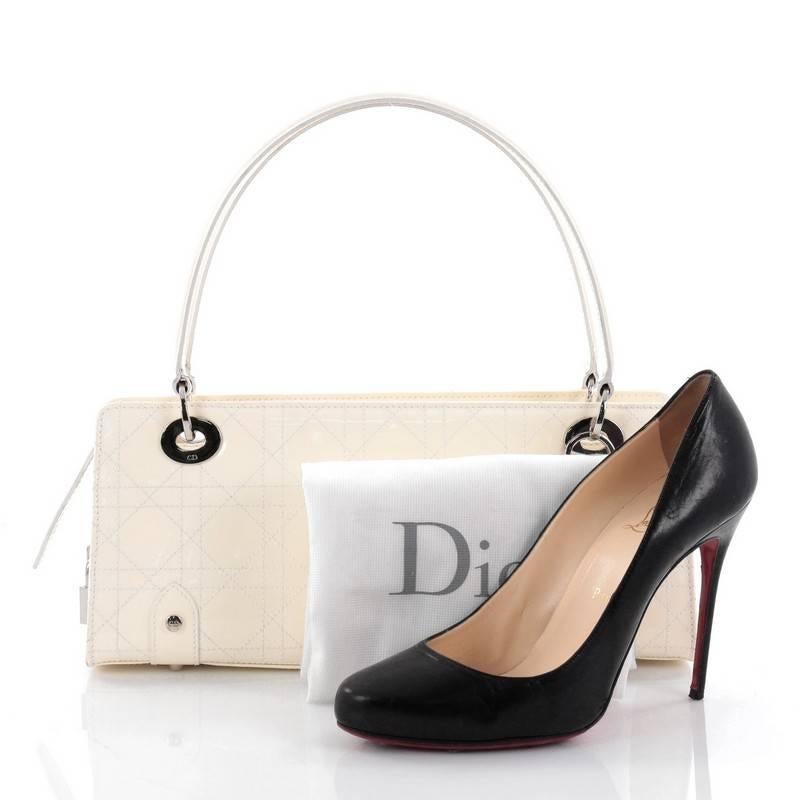 This authentic Christian Dior East West Lady Dior Handbag Stitched Cannage Patent Small is a classic and chic bag ideal for your nights out. Crafted from off-white stitched cannage patent leather, this luxurious handbag features dual flat patent