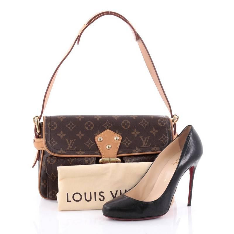 This authentic Louis Vuitton Hudson Handbag Monogram Canvas PM is casual yet classic everyday bag. Crafted from Louis Vuitton’s brown monogram coated canvas, this satchel features vachetta leather trims and strap, two exterior push-lock pockets with