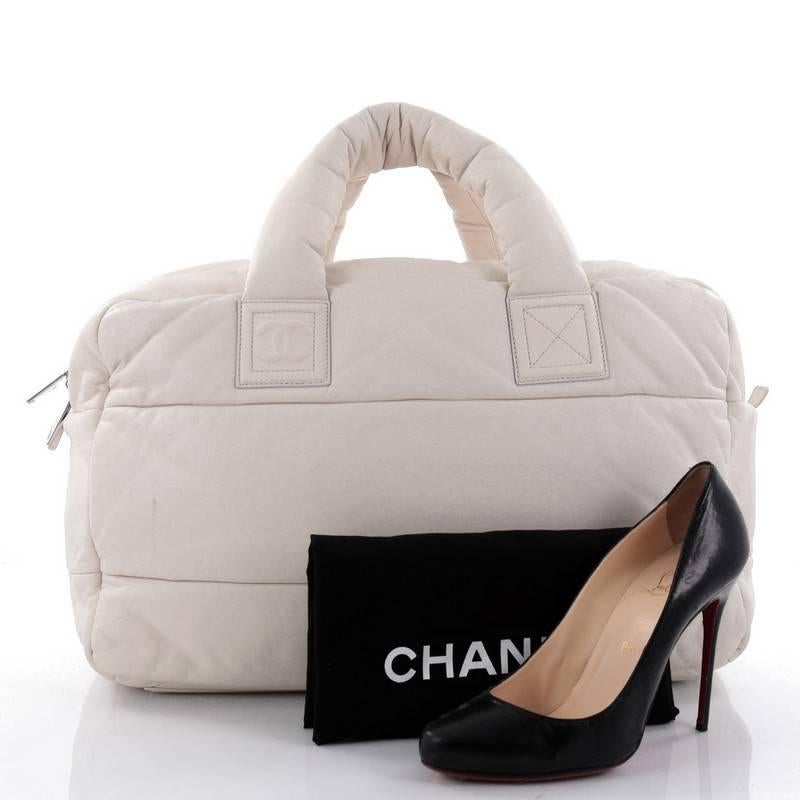 This authentic Chanel Coco Cocoon Bowling Bag Quilted Lambskin Large is a highly sought after piece from Lagerfeld's fun and chic Coco Cocoon line. Crafted from puffy off-white leather, this lightweight, stylish bowler bag features dual-padded top