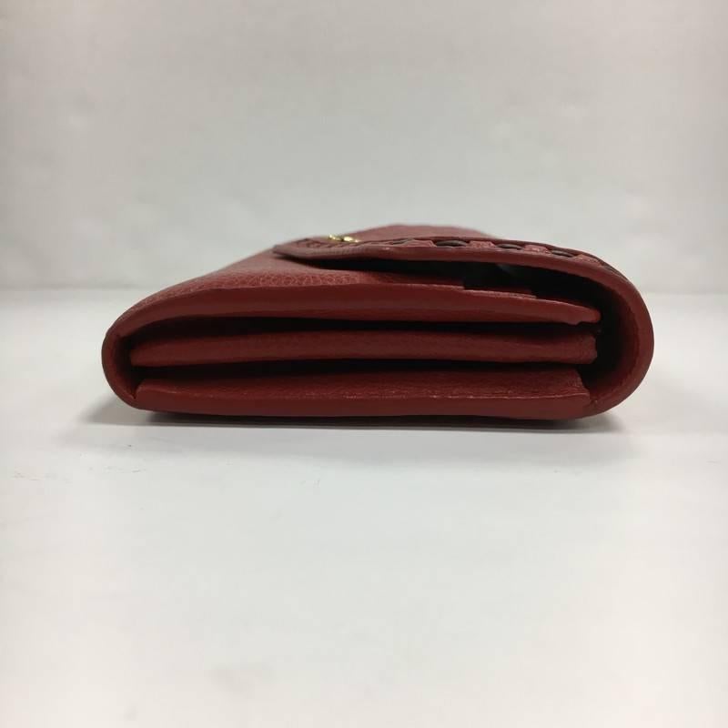 This authentic Louis Vuitton Sarah Wallet NM Monogram Empreinte Leather is a perfect small accessory to partner with any bag. Crafted from red empriente leather, this versatile wallet features an envelope-style frontal flap with snap button closure