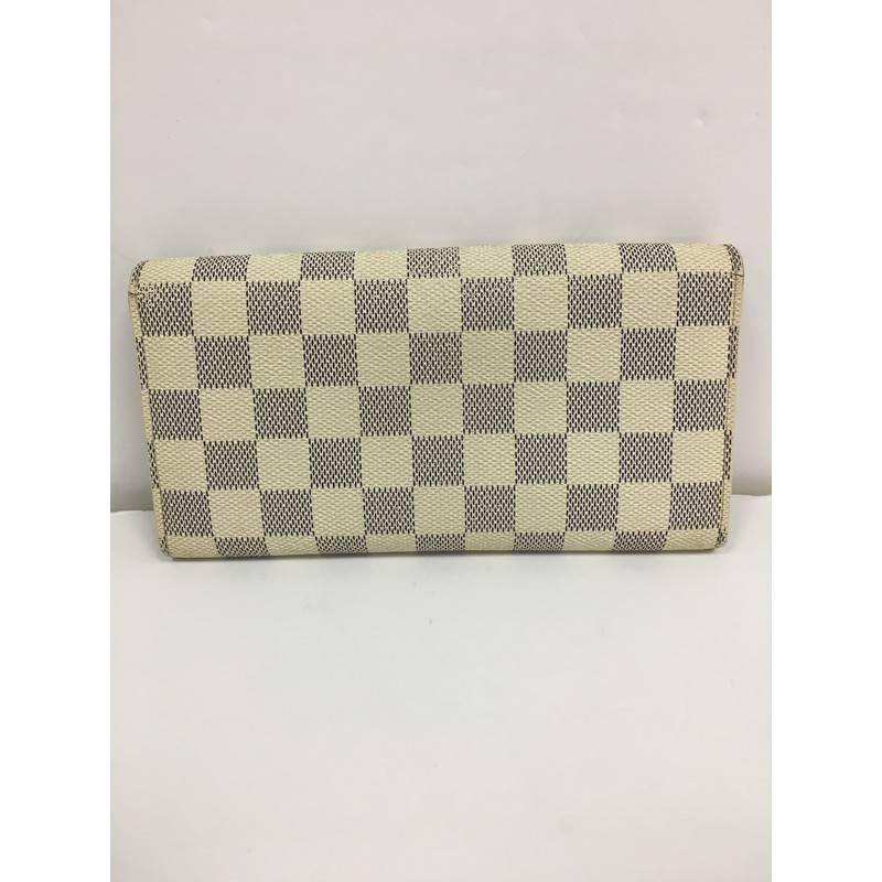 This authentic Louis Vuitton Sarah Wallet Damier is your perfect small accessory. Crafted in damier azur coated canvas, this versatile wallet features a snap button closure, gold-tone hardware accents and beige leather-lined interior with multiple