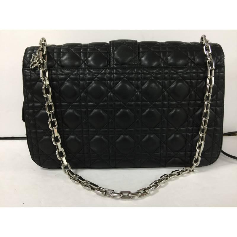 This authentic Christian Dior Miss Dior Flap Bag Cannage Quilt Lambskin Large showcases an elegant and modern design that is perfect for nights out. Crafted from black cannage quilt lambskin leather, this bag features silver-tone chain-link shoulder