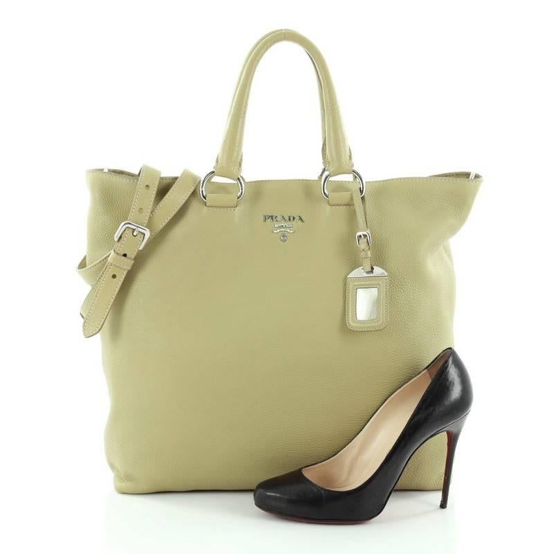 This authentic Prada Convertible Tote Vitello Daino Large is perfect for your everyday casual looks. Crafted from light green vitello daino leather, this tote features dual-rolled handles with rings, detachable shoulder strap, raised metal Prada