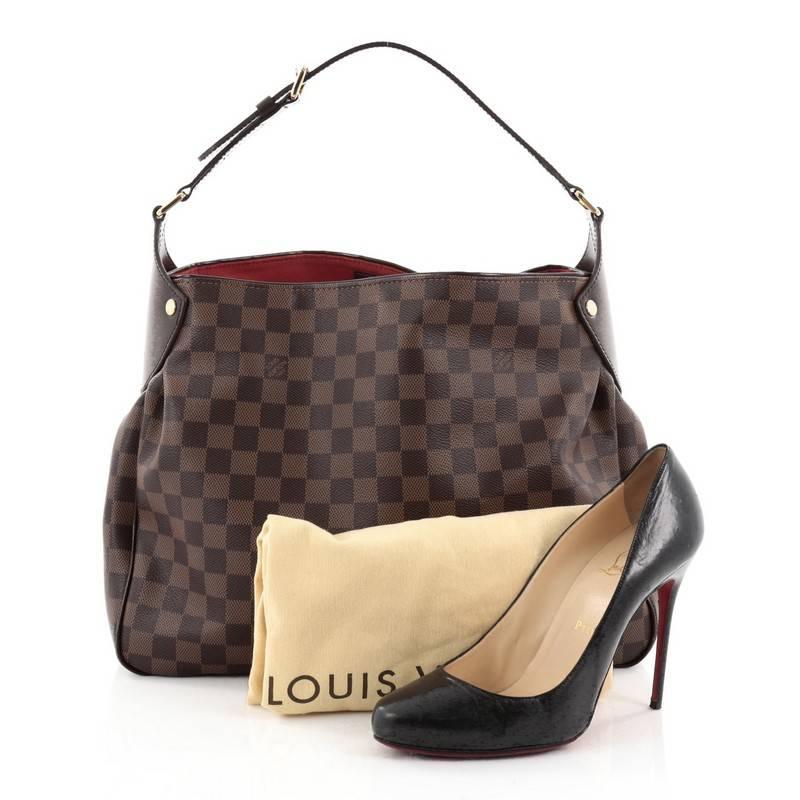 This authentic Louis Vuitton Reggia Handbag Damier is a simple and sophisticated bag that will be your new favourite everyday accessory. Crafted from damier ebene coated canvas, this bag features an adjustable shoulder strap, chocolate brown leather