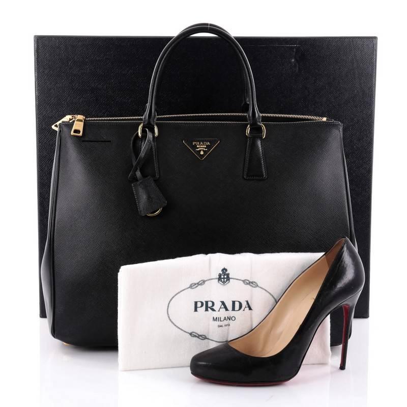 This authentic Prada Double Zip Lux Tote Saffiano Leather Large is the perfect bag to complete any outfit. Crafted from black saffiano leather, this boxy tote features side snap buttons, raised Prada logo, dual-rolled leather handles and gold-tone